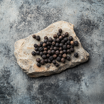 Black peppercorns, one of the natural ingredients in Sandalure 18, contributing to the fragrance's warm and spicy notes