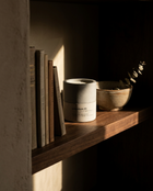 Lavendure 21 lavender eucalyptus concrete soy candle on a walnut bookshelf beside books and a ceramic bowl with a eucalyptus sprig.